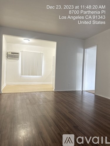 A room with wooden flooring and a window with blinds.