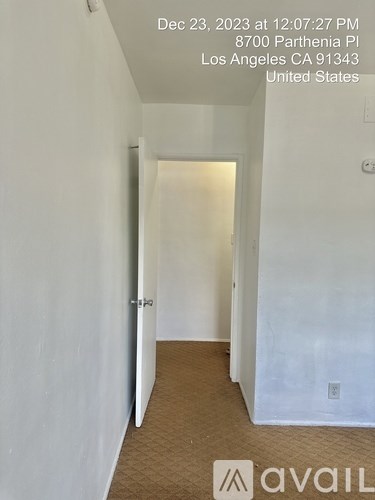 A hallway with a door on the left and a carpeted floor.