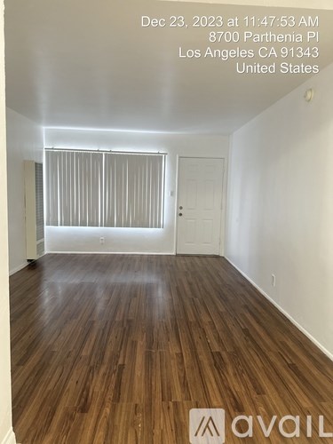 A room with wooden flooring and a window with blinds.