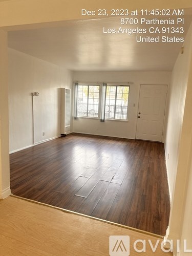 A room with wooden flooring and a window with blinds.