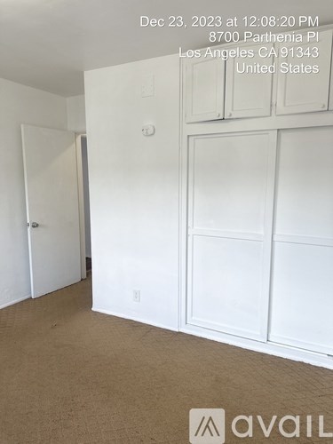 A room with white cupboards and a brown carpet.