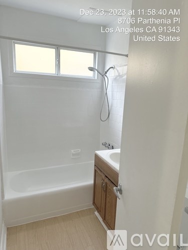 A bathroom with a white tub, sink, and wooden cabinet.