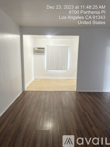 A room with wooden flooring and a window with blinds.