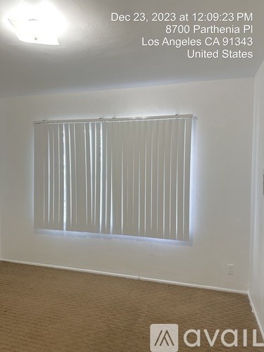 A room with a window covered by vertical blinds.