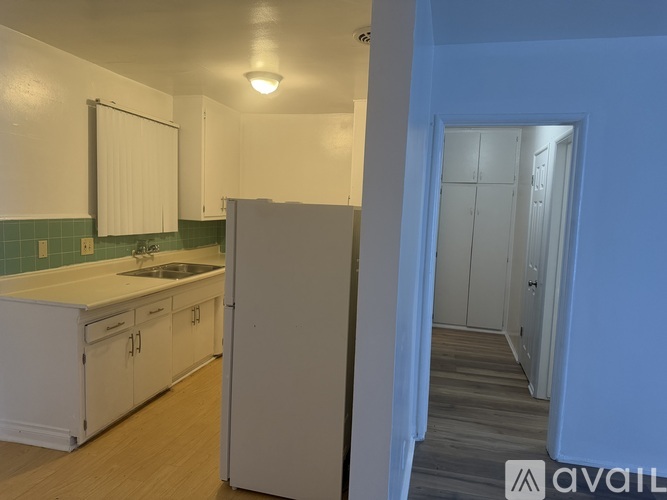 A white gas stove in a kitchen with a white wall and a white fridge.