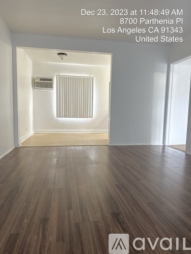 A room with wooden flooring and a window with blinds.