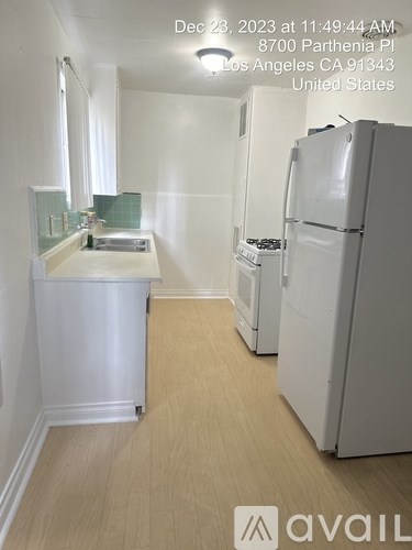 A white kitchen with a refrigerator and sink.