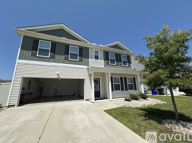A two-story house with a garage and a tree in front.