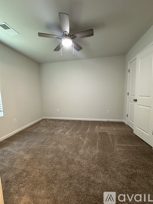 A room with a ceiling fan and carpeted floor.