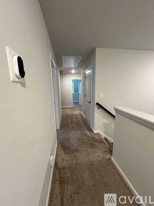 A hallway with a carpeted floor and white walls.