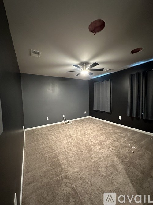 A room with a carpeted floor and a ceiling fan.
