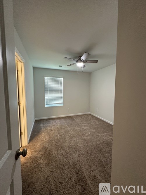 A room with a carpeted floor and a ceiling fan.
