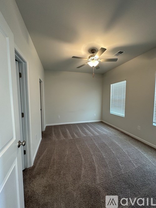 A room with a carpeted floor and a ceiling fan.