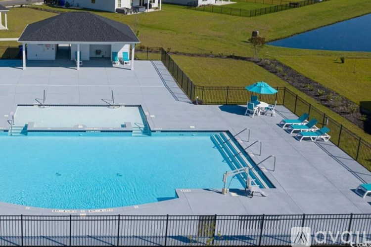 A pool with a diving board and chairs around it.