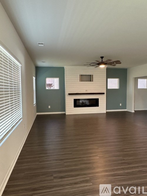 A spacious room with a fireplace and wooden floors.