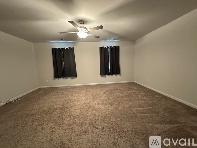 A room with a carpeted floor and a ceiling fan.