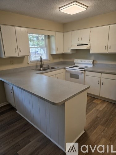 A kitchen with white cabinets and a wooden floor.