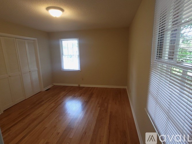 A room with wooden flooring and a window with blinds.