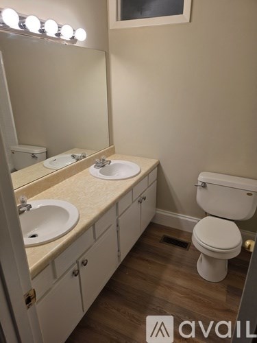 A bathroom with a toilet, sink, and mirror.