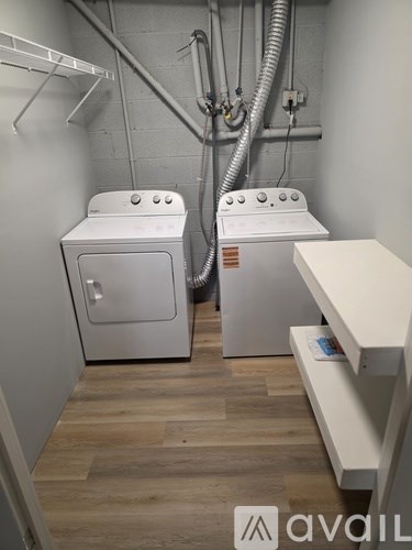 A laundry room with a washer and dryer and a shelf.
