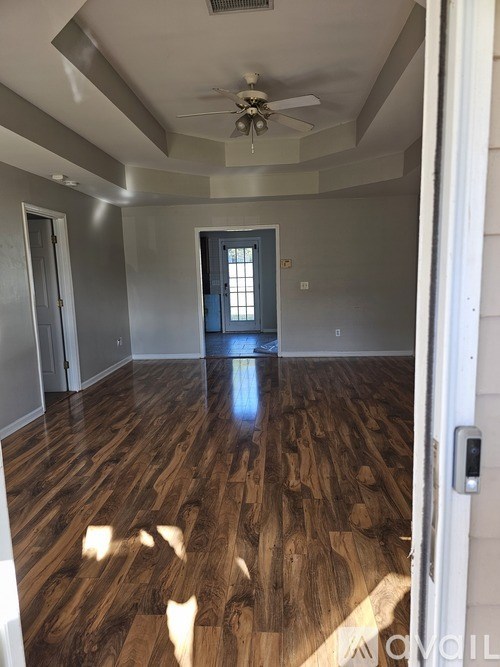 A room with wood flooring and a ceiling fan.