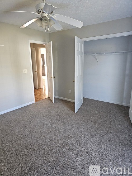 A room with a ceiling fan and carpeted floor.