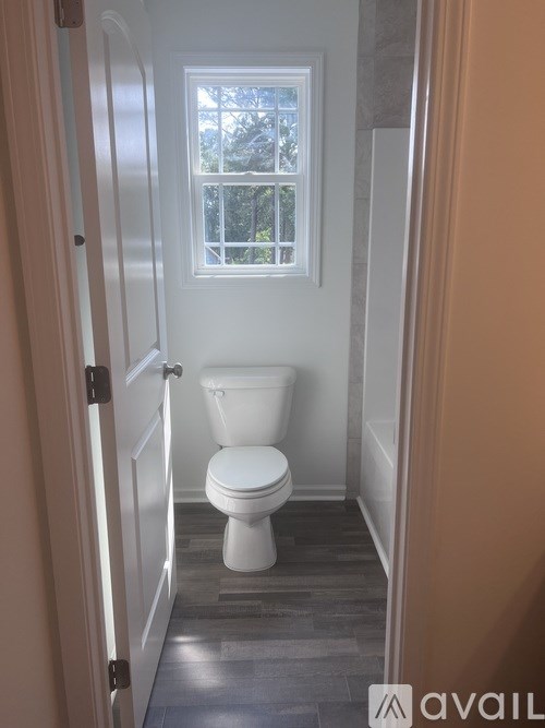 A white toilet in a bathroom with a window.