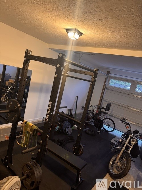 A gym with a squat rack, weights, and a motorcycle.