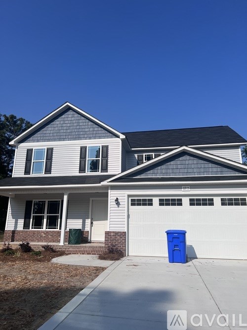 A house with a blue bin in front of it.