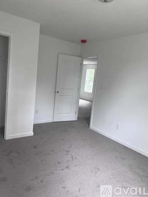 A room with a carpeted floor and a door leading to a hallway.