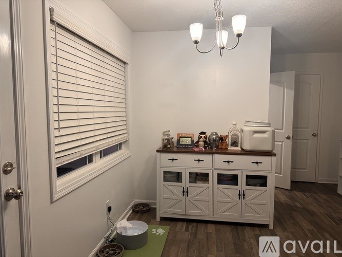 A kitchen with a white cabinet and a window with blinds.