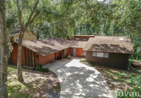A house with a brown roof is surrounded by trees.