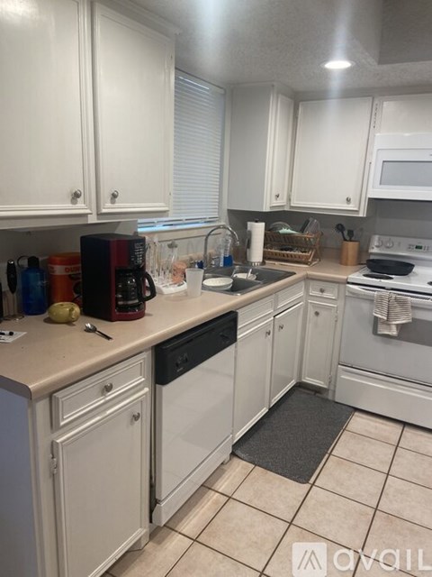A kitchen with white cabinets and appliances.