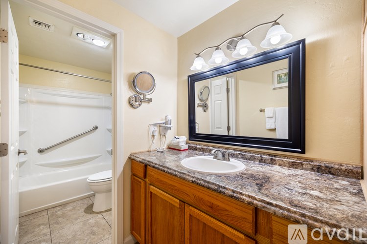 A bathroom with a marble countertop and a large mirror above it.