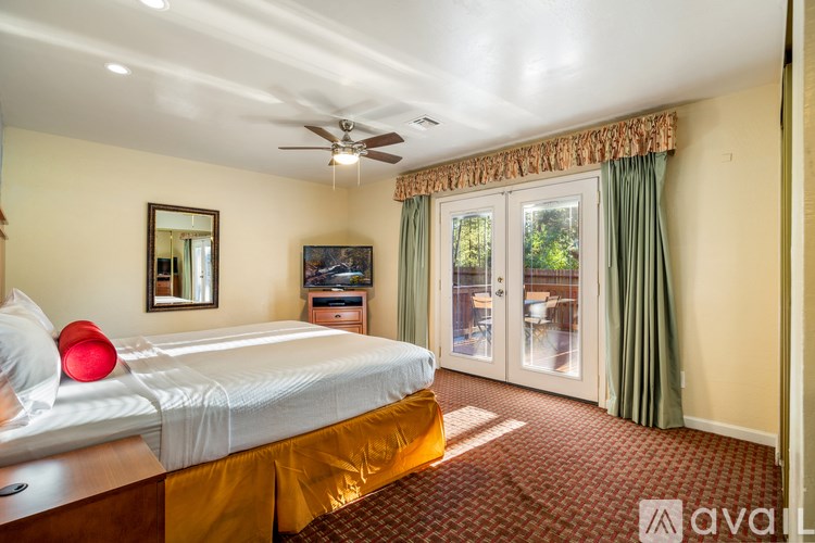 A bedroom with a bed, dresser, and sliding glass doors.