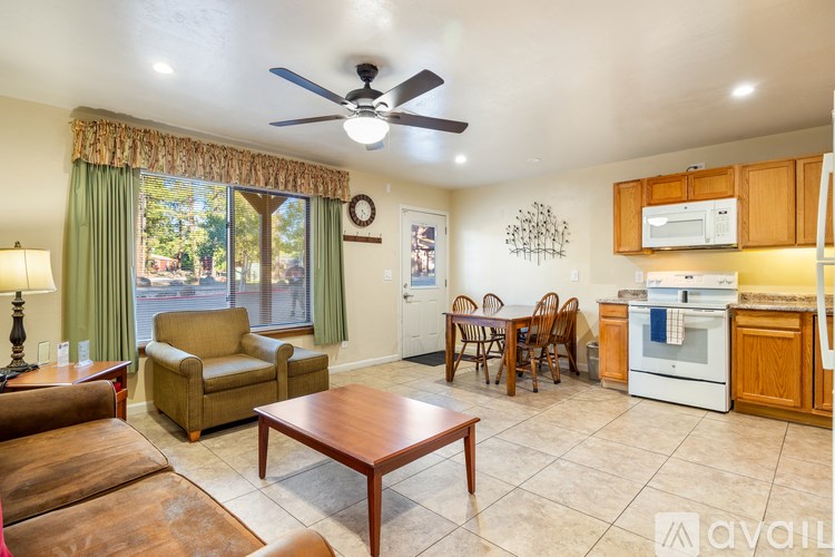 A living room with a brown couch, a coffee table, and a ceiling fan.