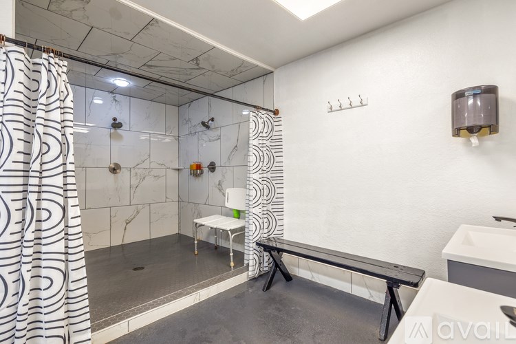 A bathroom with a shower, sink, and a bench.