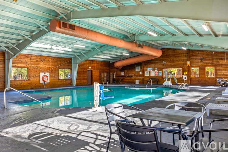 A large indoor swimming pool with a table and chairs around it.