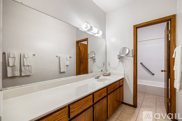 A bathroom with a white countertop and wooden cabinets.