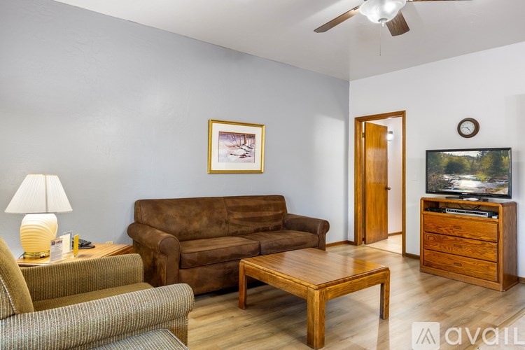A living room with a brown couch, a wooden coffee table, and a flat screen TV.