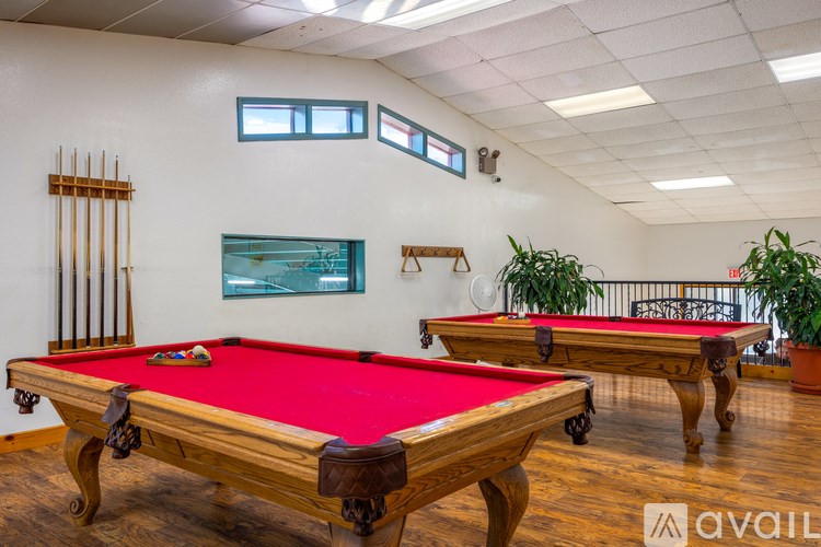 A pool table with a red cloth and a pool cue on it.