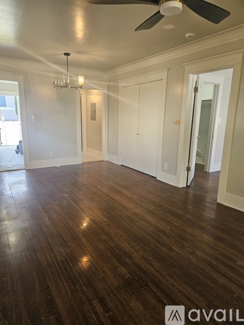 A spacious room with wood flooring and a ceiling fan.