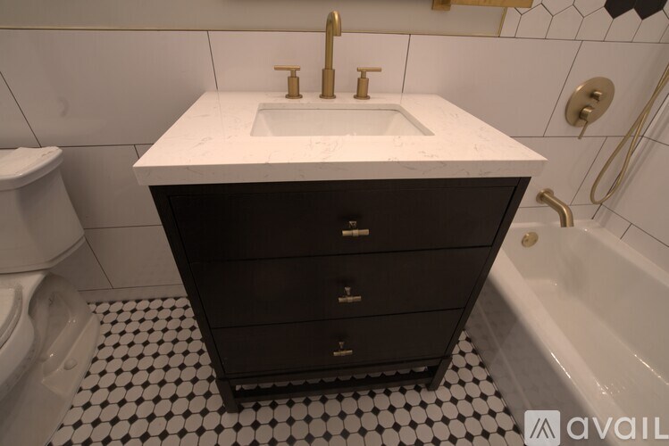 A white sink with a gold faucet is on top of a black cabinet in a bathroom.