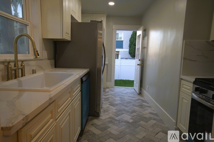 A kitchen with a sink, refrigerator, and a window.