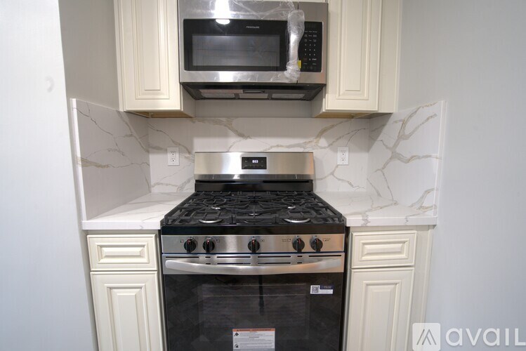 A black stove top oven with a white microwave above it.