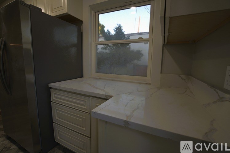 A kitchen with a black refrigerator and white marble countertops.