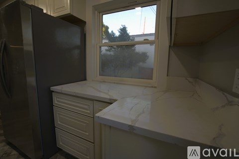 A kitchen with a black refrigerator and white marble countertops.