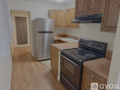 A kitchen with wooden cabinets and a stainless steel refrigerator.