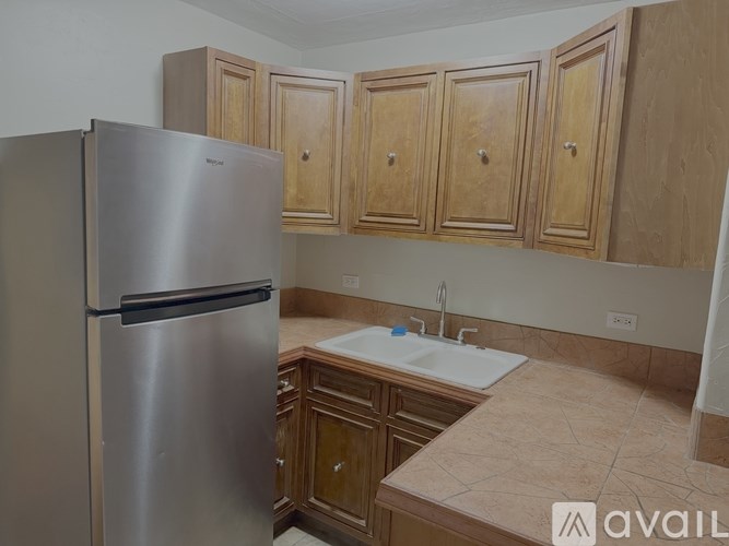 A kitchen with a stainless steel refrigerator and wooden cabinets.