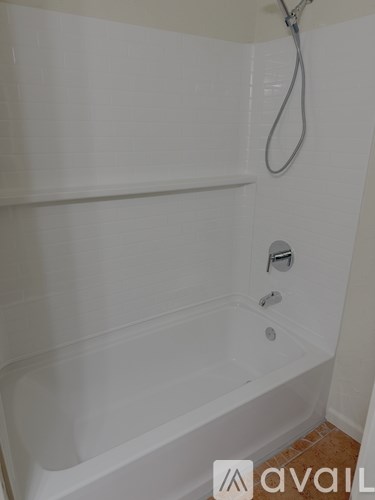 A white bathtub with a shower head and faucet.